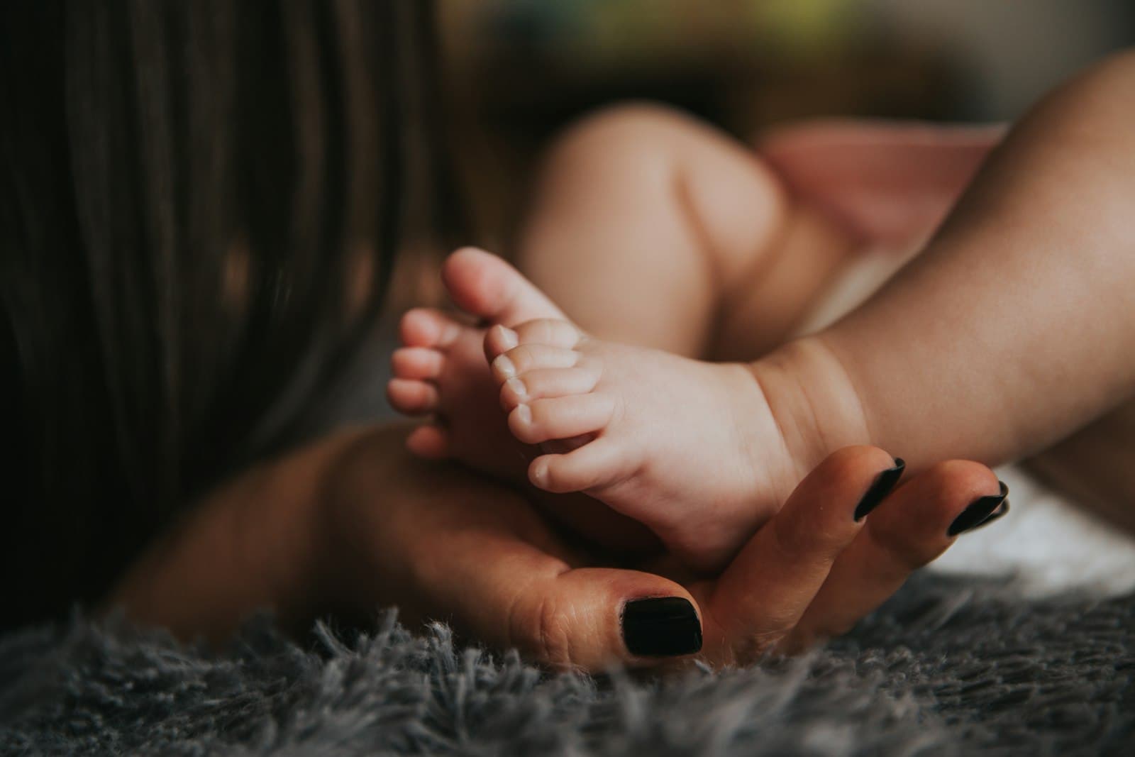 A newborn's feet held in a woman's hand
