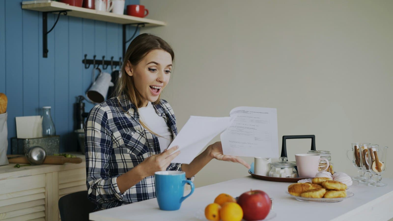 A woman at a table reading through a stack of documents, looking surprised